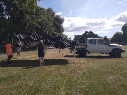 A group of people standing next to a white truck

Description automatically generated
