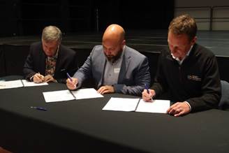 A group of men signing papers

Description automatically generated