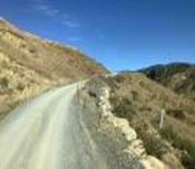 A road with grass and blue sky

Description automatically generated