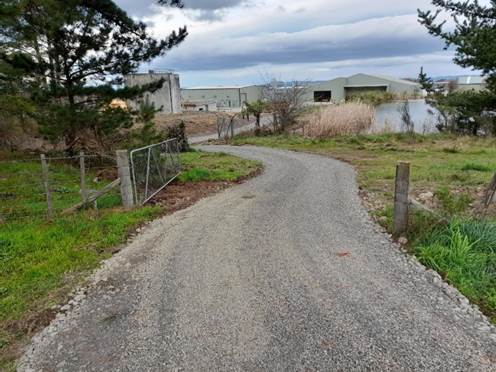 A gravel path with trees and a fence

Description automatically generated