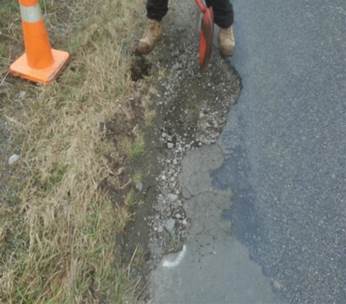 A person holding a shovel in front of a road

Description automatically generated