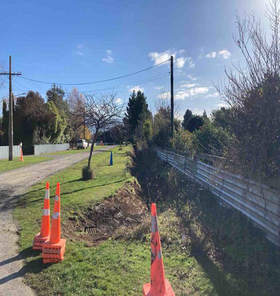 A road with orange cones and a fence

Description automatically generated