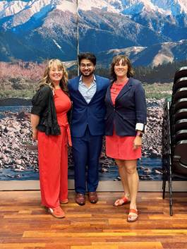 A group of people standing in front of a wall with a mountain backdrop

Description automatically generated