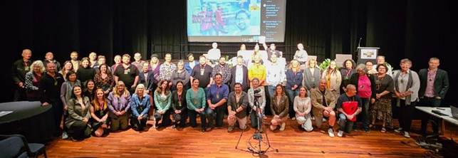 A group of people standing on a stage

Description automatically generated