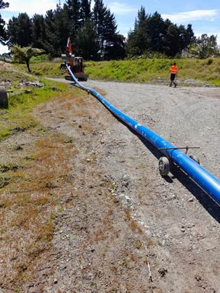 A long pipe on a dirt road

Description automatically generated