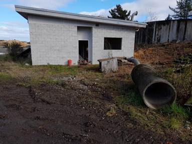 A building with a pipe in the dirt

Description automatically generated