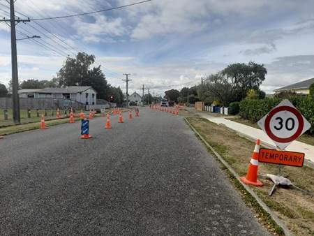 A road with cones and a sign

AI-generated content may be incorrect.