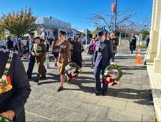 A group of people walking with wreaths

AI-generated content may be incorrect.