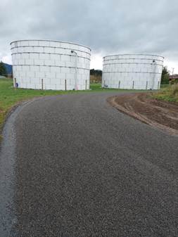 A road leading to two white silos

AI-generated content may be incorrect.