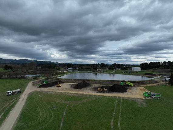 A field with dirt and dirt near a pond
AI-generated content may be incorrect.